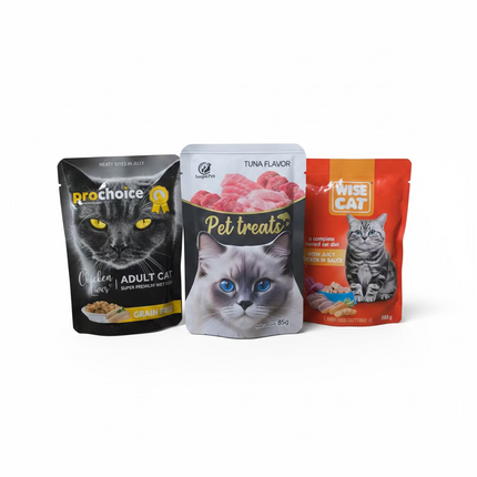 Three cat food packages on a grassy surface with a beige wall background