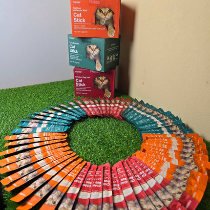 Cat food sticks arranged in a circular pattern with boxes stacked in the background.